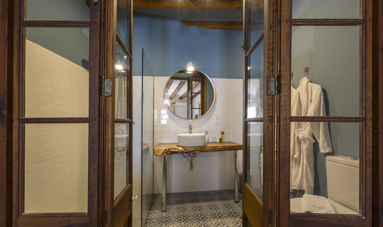 Een badkamer met een houten wastafelmeubel, een ronde spiegel en een wit toilet.