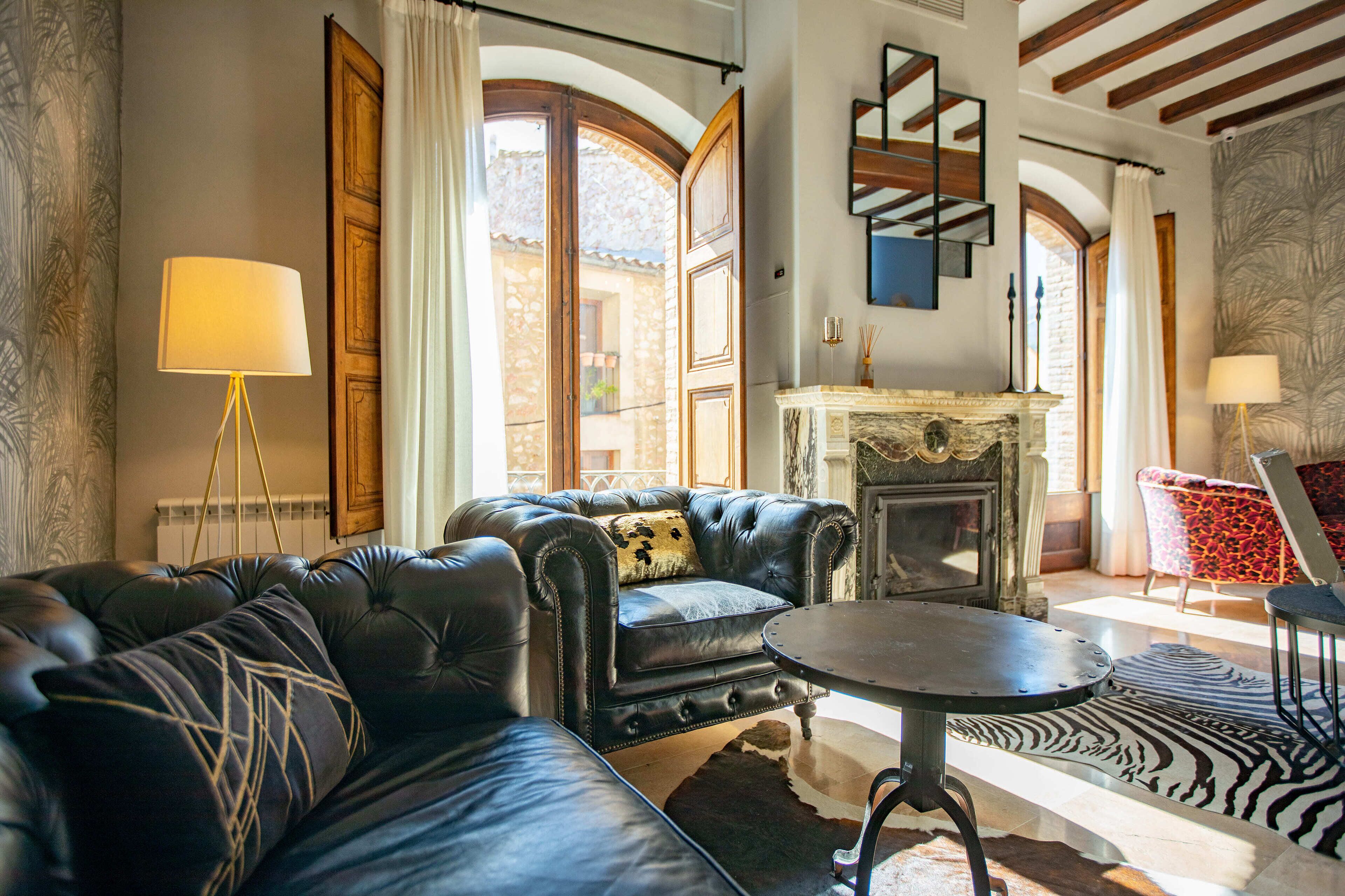 Una sala de estar con sofá de cuero, una mesa de centro redonda y una chimenea.