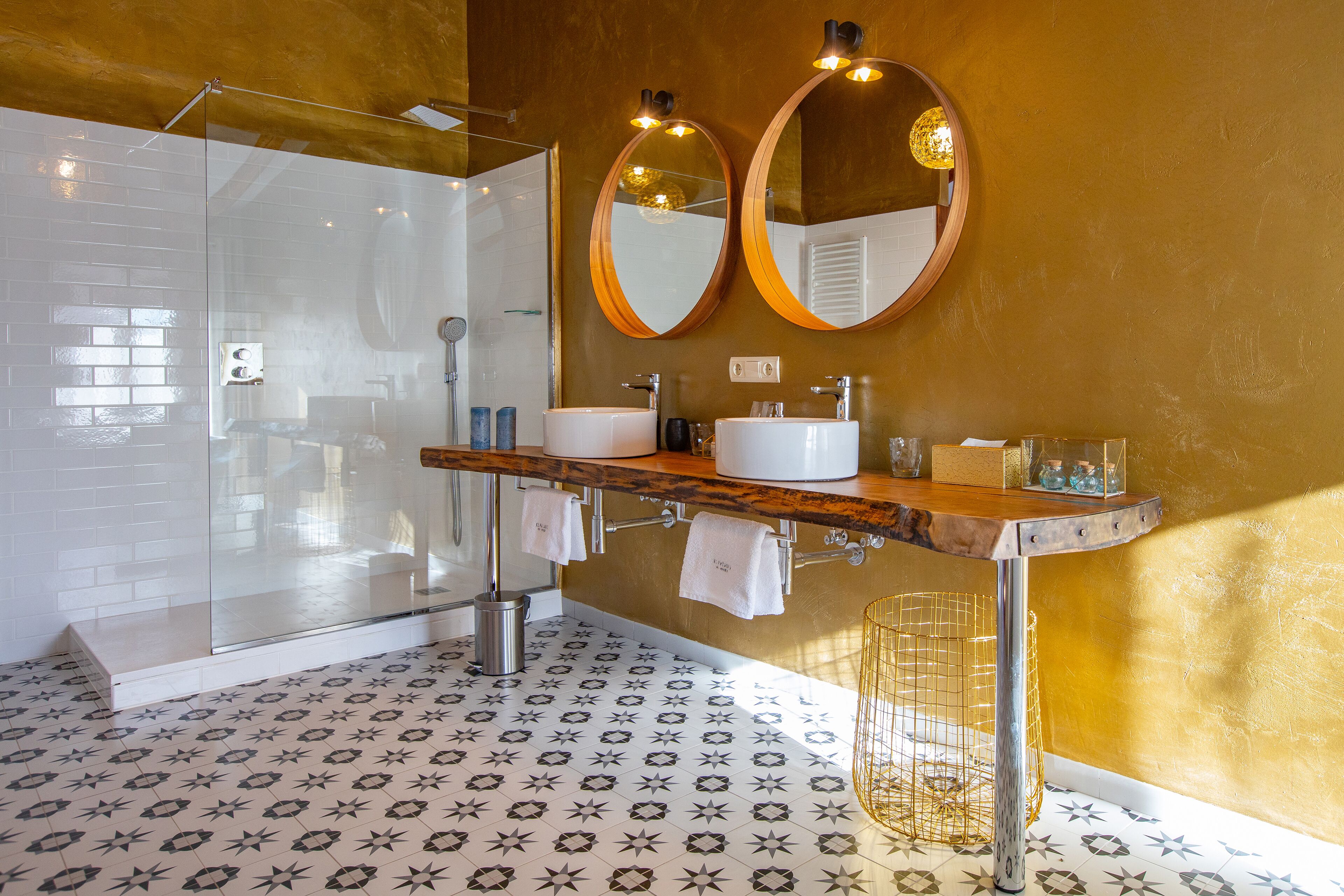 A modern bathroom with a glass shower enclosure, a double sink vanity with a wooden countertop, and a large mirror above the sink.