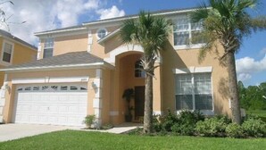 A two-story house with a garage, palm trees, and a well-maintained lawn.