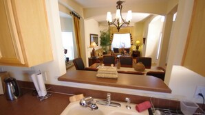 A kitchen with a sink, a coffee maker, and a tea kettle. There is a dining area with a table and chairs.