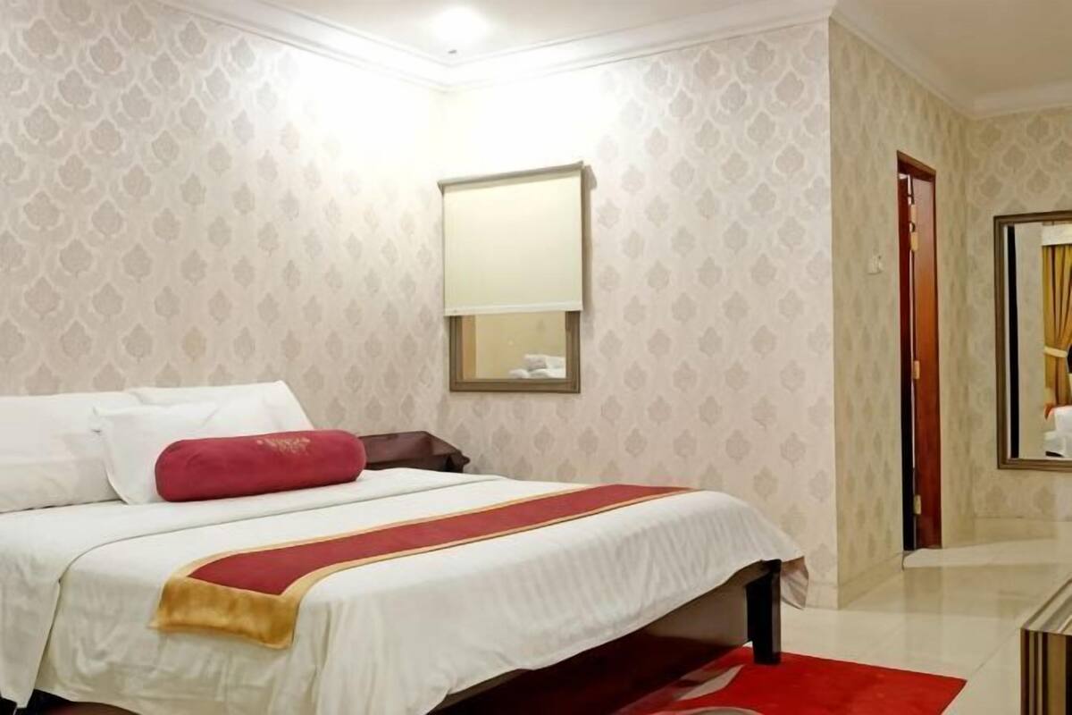 A hotel room with a bed, a mirror, and a door.