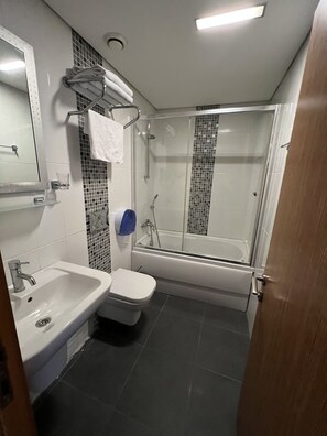 A modern bathroom with a shower, toilet, sink, and a glass shower door. - Aycan Sultan Apart Hotel (Istanbul)