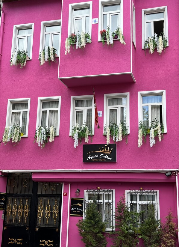 A pink building with multiple windows, some with hanging flower baskets. - Aycan Sultan Apart Hotel (Istanbul)
