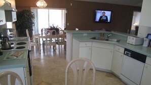 A kitchen with a dining area, a television mounted on the wall, and a Winnie the Pooh figurine on the table. - Ly53774 - Indian Ridge - 4 Bed 2 Baths Villa (Kissimmee)
