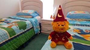 A child's bedroom with two beds, each with a colorful quilt and matching pillows. A teddy bear wearing a red hat is placed on the floor between the beds. - Ly53774 - Indian Ridge - 4 Bed 2 Baths Villa (Kissimmee)