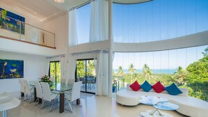 A spacious living area with a glass dining table, white chairs, and a modern sofa with colorful cushions. - White Stone (Koh Samui)