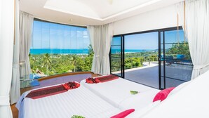 A bedroom with two beds, large windows, and a balcony with a view of the sea. - White Stone (Koh Samui)