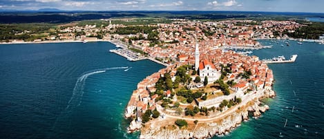 An aerial view of a coastal town with a prominent fortress-like structure surrounded by water.