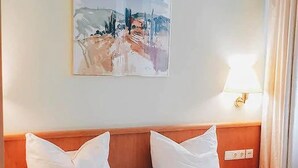 Una habitación de hotel con una cama, una mesita de noche, una lámpara y un cuadro en la pared.