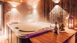 Un espace de détente en bois avec un jacuzzi, une bouteille de vin et des verres sur une table en bois.