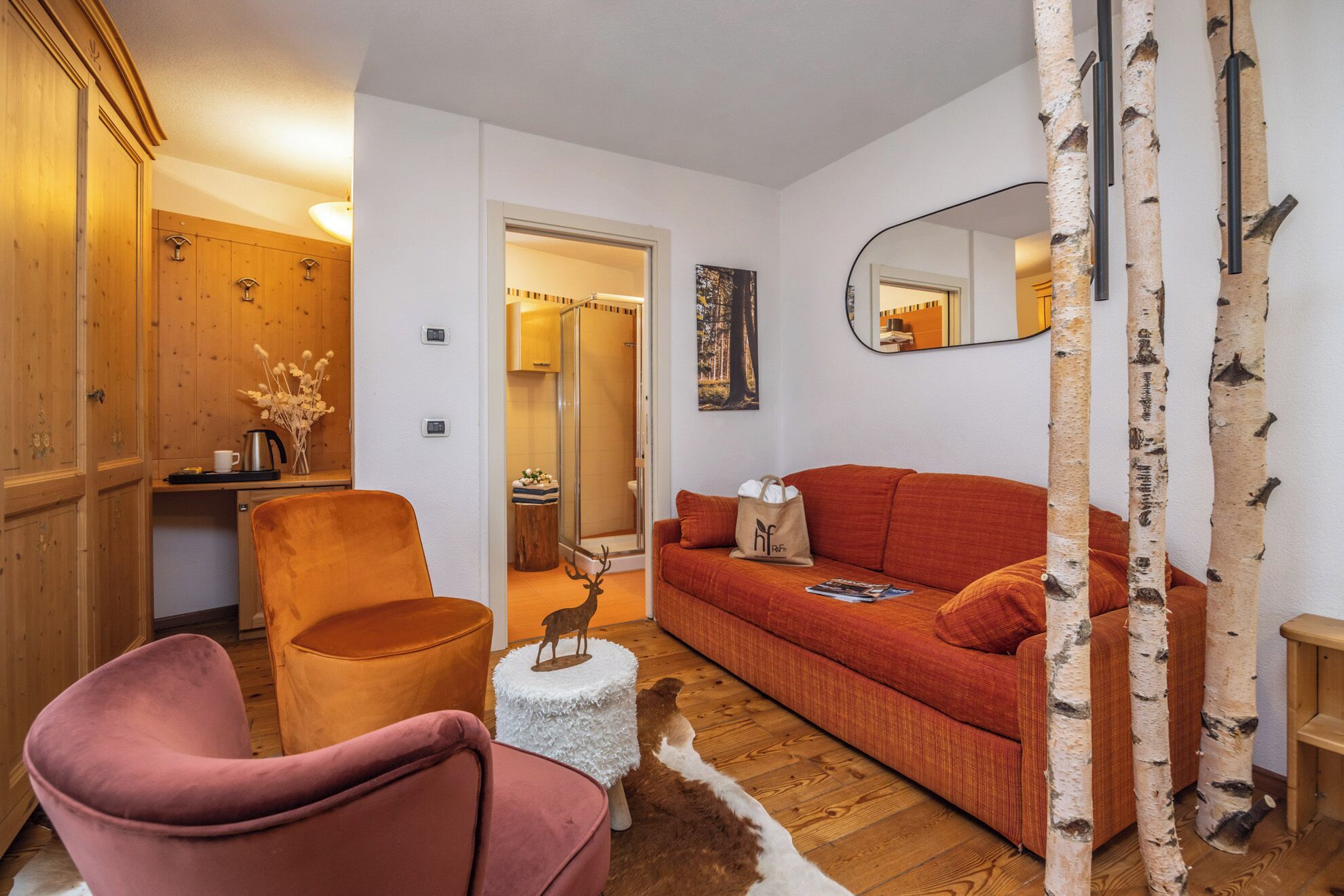 A cozy living room with a sofa, armchair, and birch trees.