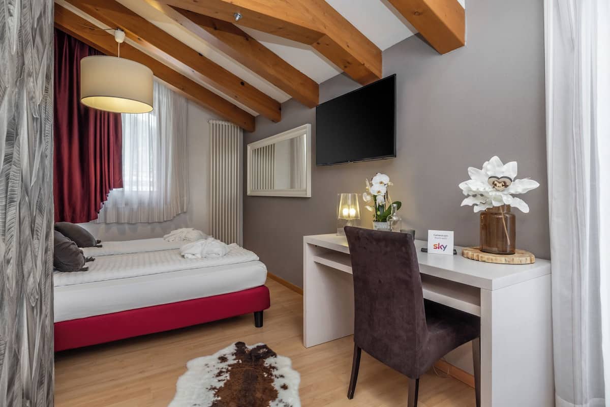 Ein Schlafzimmer mit Bett, Schreibtisch, Stuhl und Fernseher.