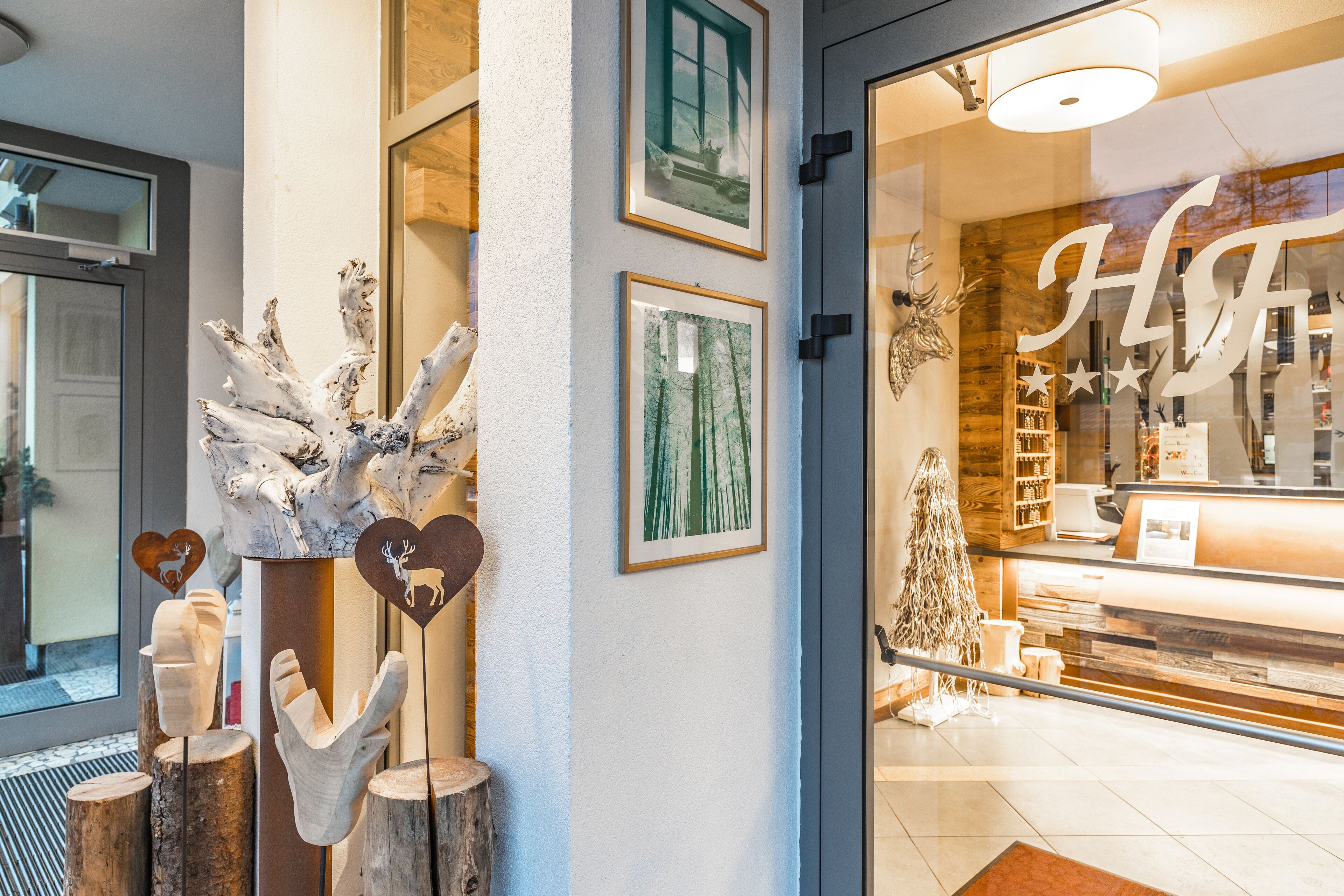 A hotel lobby with a reception desk, framed pictures on the wall, and wooden decor elements.