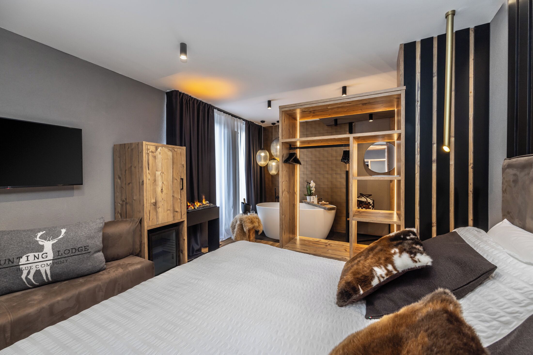 Una camera d'albergo moderna con un letto grande, un armadio in legno, un box doccia e una TV a schermo piatto.