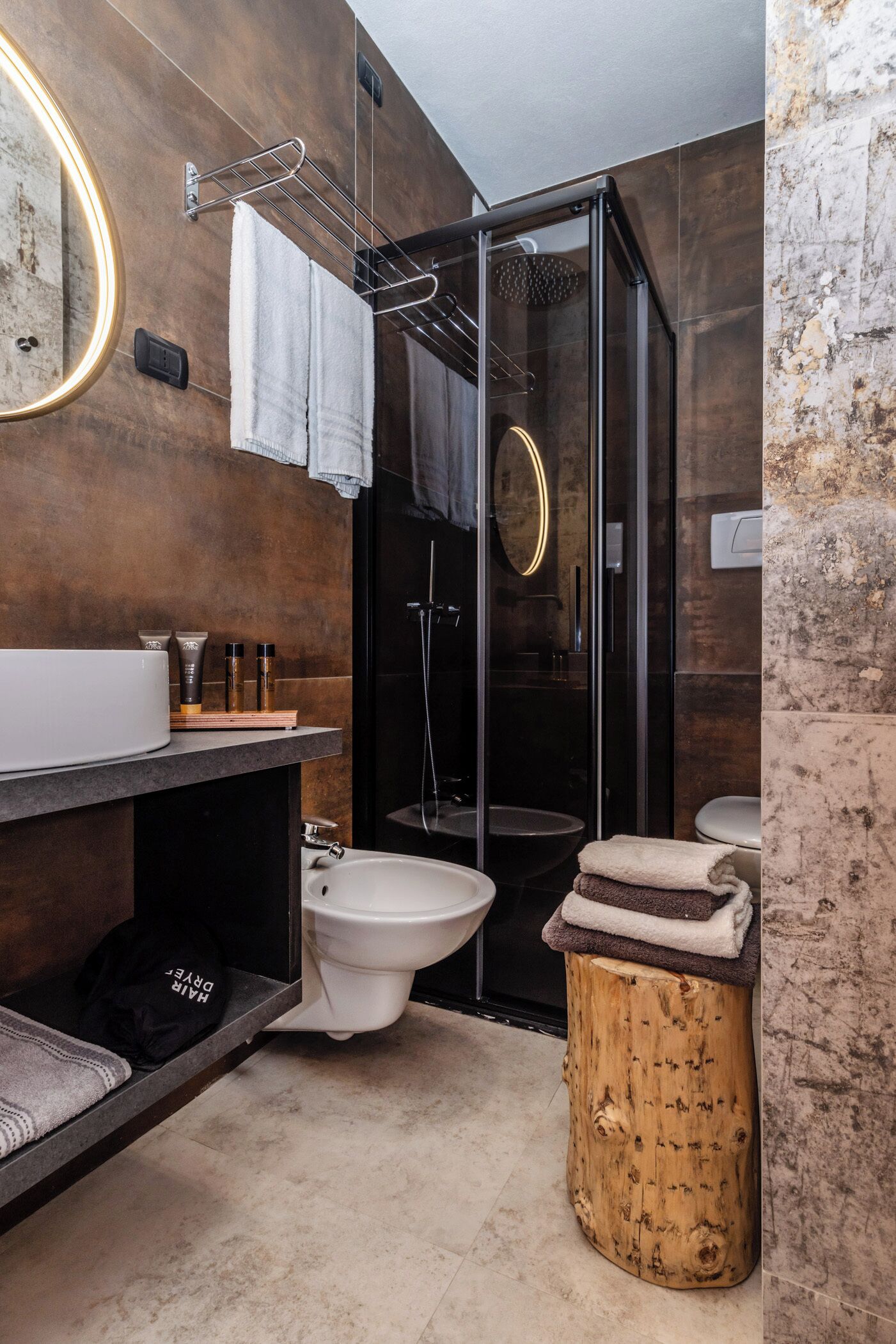 A modern bathroom with a wooden vanity, a glass shower enclosure, and a round mirror.