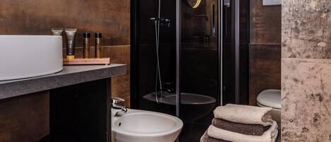 A modern bathroom with a wooden vanity, a glass shower enclosure, and a round mirror.
