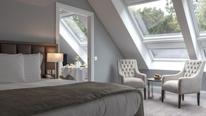 A hotel room with a large bed, a sitting area with two armchairs, a small table, and a breakfast setup. - Ness Walk (Inverness)