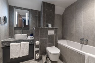 Un baño moderno con lavamanos, espejo, inodoro y bañera.