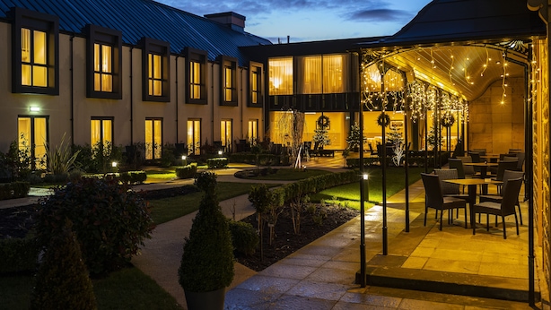 A courtyard with a covered seating area, a building with multiple windows, and a well-maintained garden. - Ness Walk (Inverness)