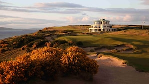 A multi-story building with a green roof, situated on a golf course with sand bunkers and a view of the sea. - Ness Walk (Inverness)