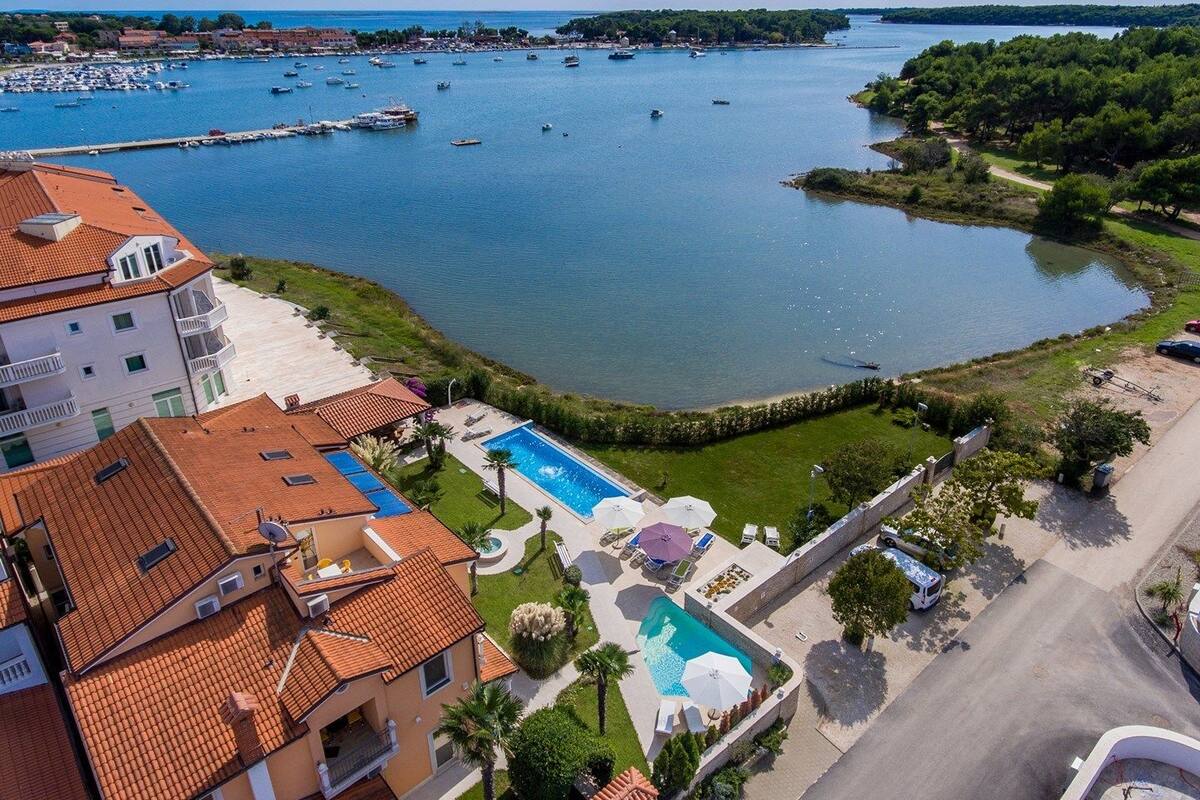 A coastal hotel with a swimming pool, a marina, and a view of the sea.