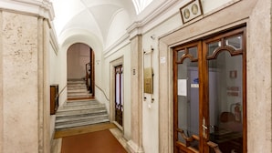 A hallway with marble walls, a wooden door, and a staircase leading to an upper floor. - AmoRoma Suite (Rome)
