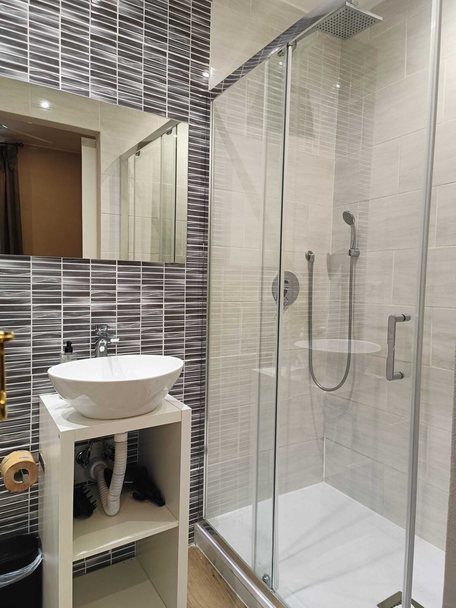Une salle de bain moderne avec une douche à parois de verre, un lavabo blanc et un miroir au-dessus du lavabo.