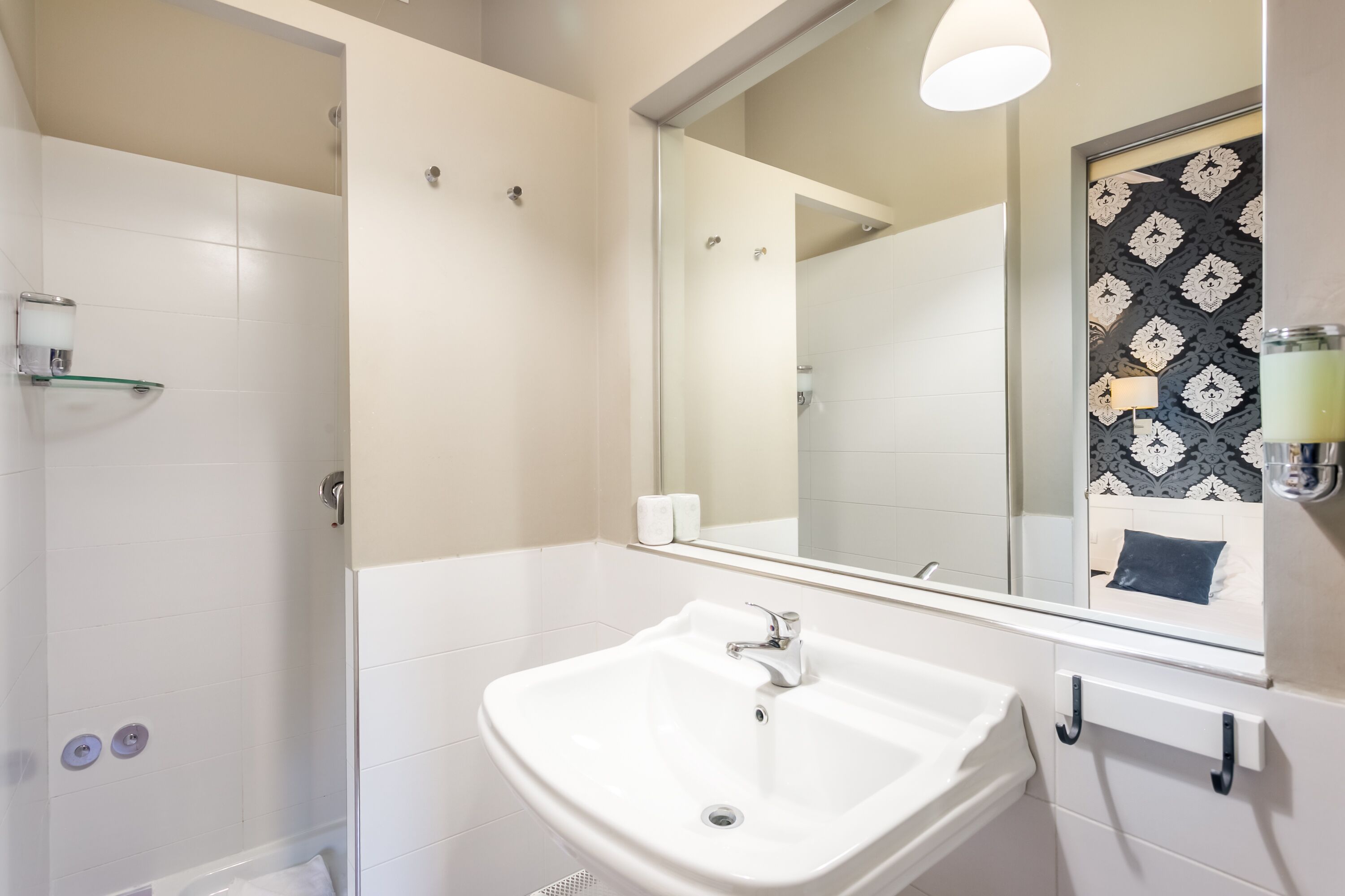 A modern bathroom with a white sink, mirror, and shower.