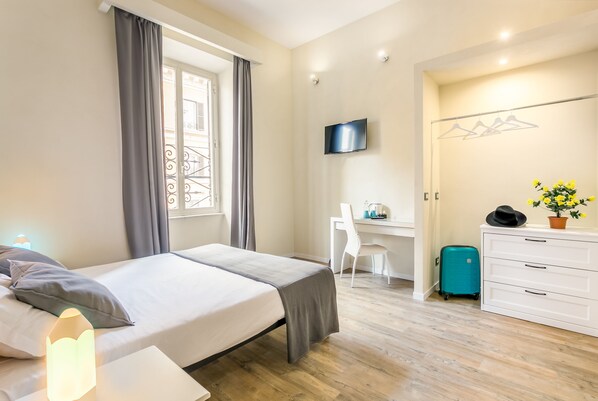 Una habitación de hotel moderna con una cama, un escritorio, un televisor y una maleta.