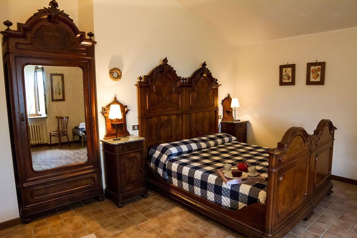 A bedroom with a large wooden bed, two bedside tables with lamps, a wooden dresser, and a mirror.