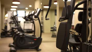 Ein Fitnessstudio mit Trainingsgeräten, darunter Laufbänder und Kraftgeräte, sowie eine Spiegelwand.
