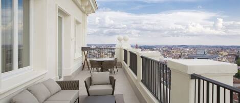 Un balcón con sofá, sillas y mesa, con vista a la ciudad.
