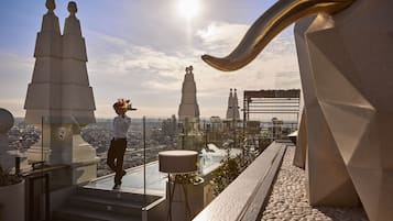 Terraza en la azotea con vistas despejadas del paisaje urbano, que destaca por su arquitectura moderna y una barandilla de vidrio.