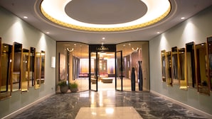 A hotel lobby with a circular ceiling light, a reception desk, and a seating area with sofas. - Hotel Riu Plaza España (Madrid)