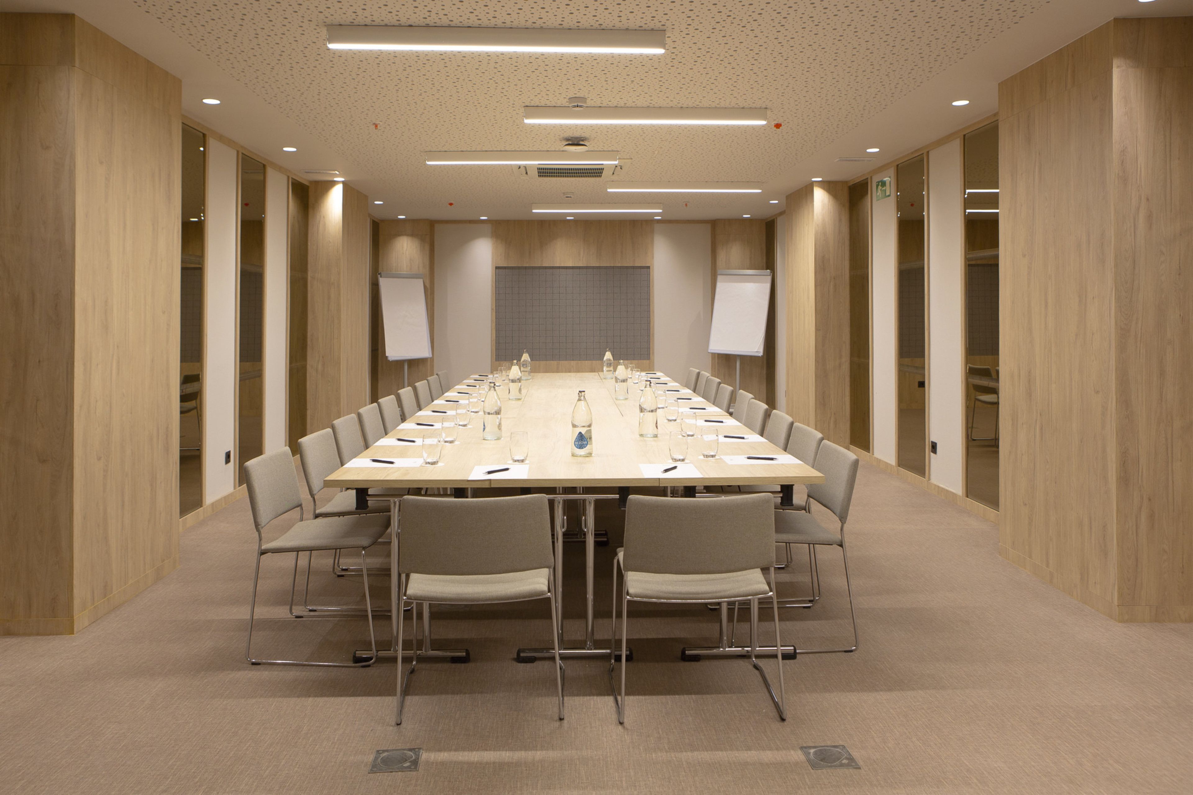 A conference room with a long table, chairs, a whiteboard, and a projector screen.