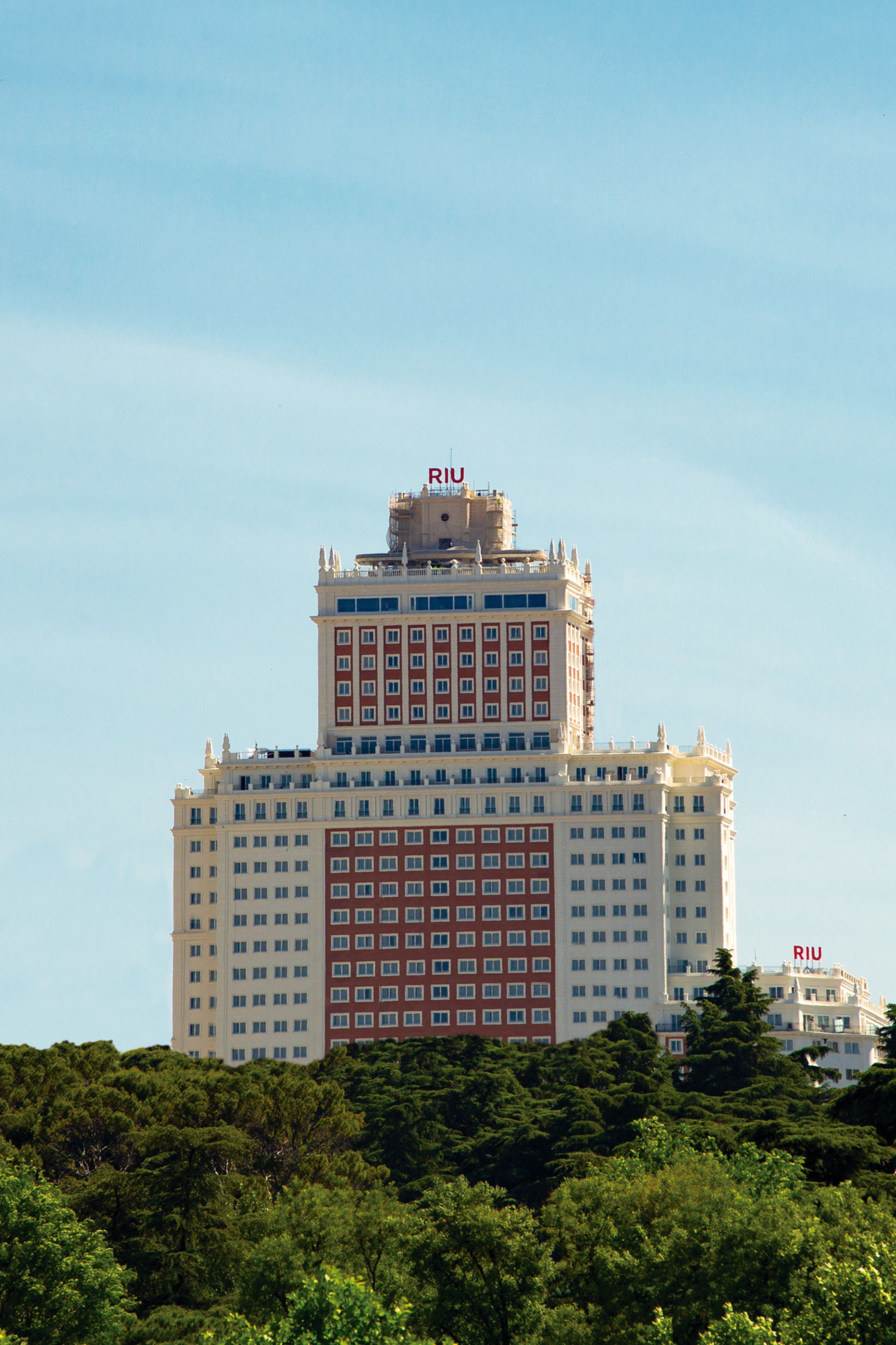 Un hotel de varios pisos con una torre central destacada y un edificio más pequeño a la derecha.