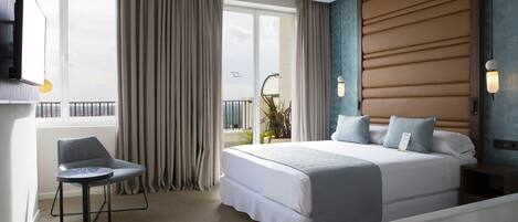 A hotel room with a large bed, a chair, a bathtub, and a view of the outdoors.