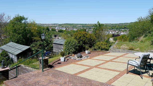 A patio area with a brick floor, a table with chairs, and a view of a town in the distance. - Heathwood BnB (Dover)
