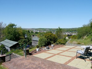 A patio area with a brick floor, a table with chairs, and a view of a town in the distance. - Heathwood BnB (Dover)
