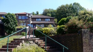 A brick staircase leading to a residential building with a tiled roof, surrounded by greenery and a clear sky. - Heathwood BnB (Dover)