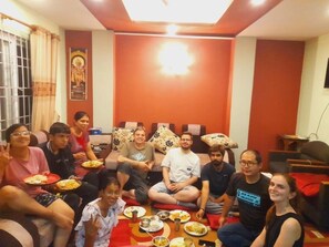Un grup de persones assegudes en un sofà i a terra en una habitació amb una paret vermella i una làmpada al sostre.
