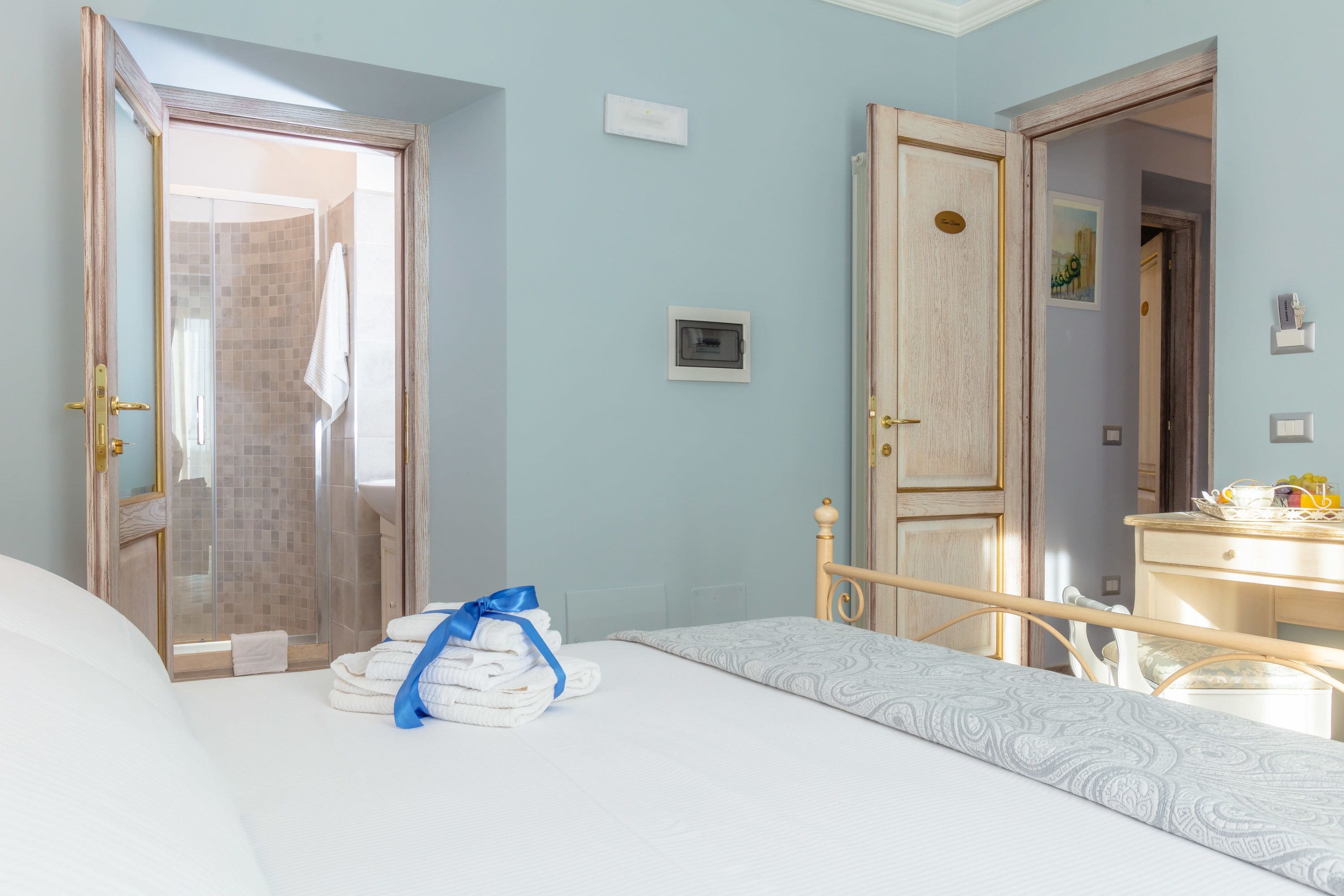 Habitación de hotel con cama, baño con ducha y escritorio con silla.
