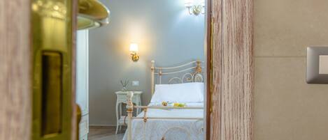 A bedroom with a bed, bedside table, lamp, and wall-mounted light fixture.