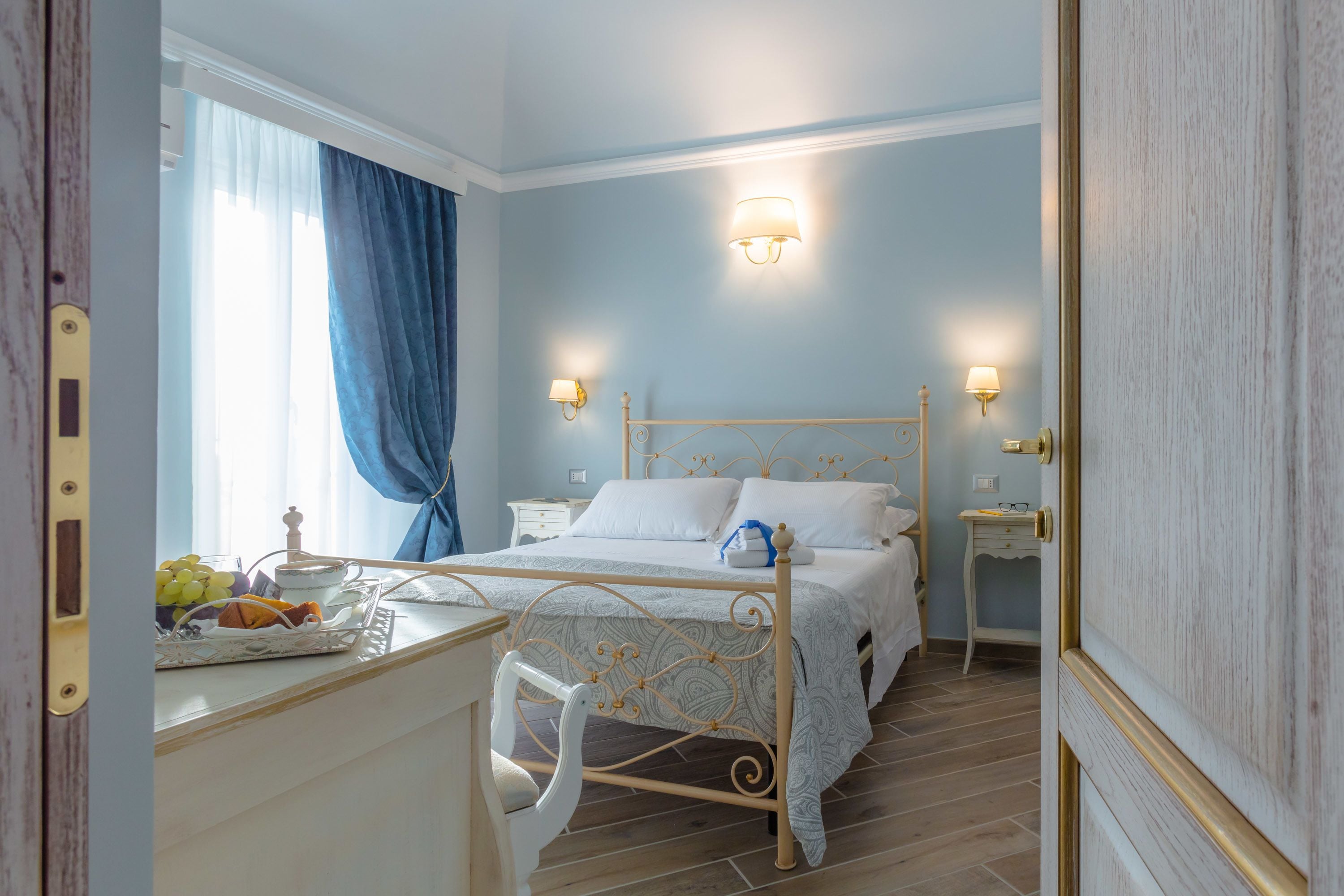 A bedroom with a bed, bedside tables, a desk with a chair, and a window with curtains.
