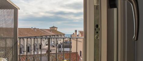 Un balcón con una mesa lista para el desayuno, una silla y vistas a edificios al fondo.