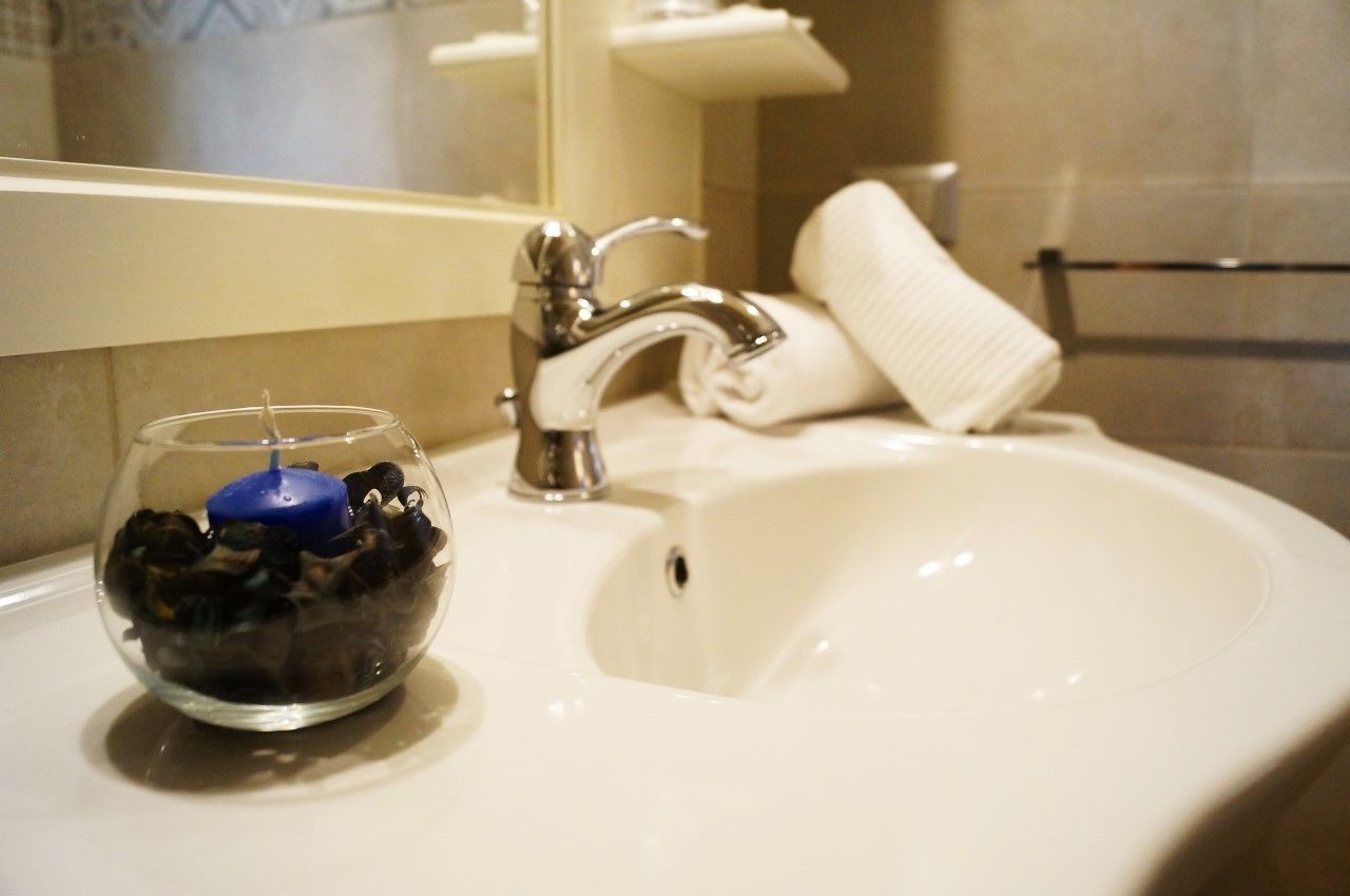 A bathroom sink with a mirror above it, a towel rack, and a glass bowl with a candle.