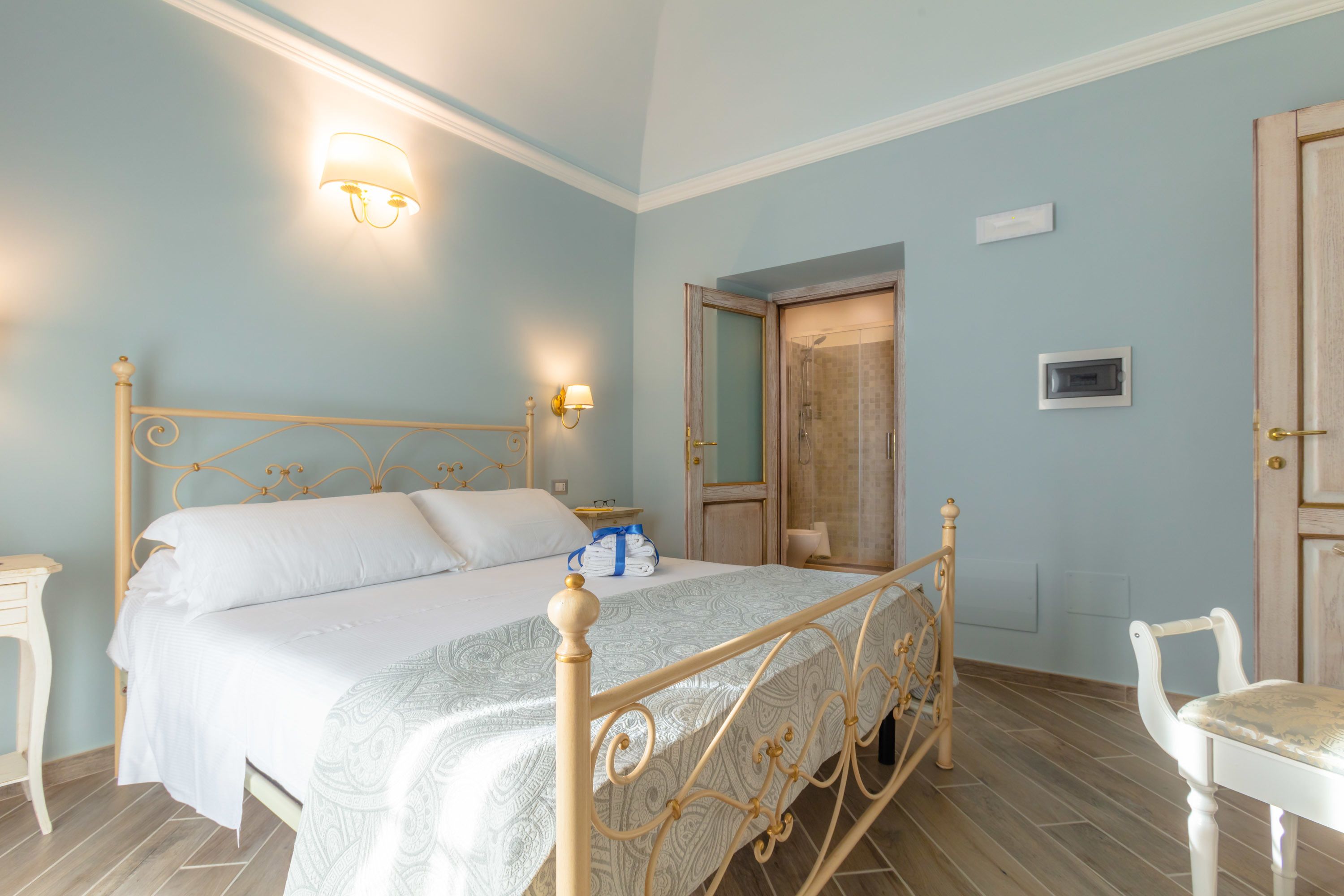 Un dormitorio con cama, mesitas de noche, una silla y una puerta.