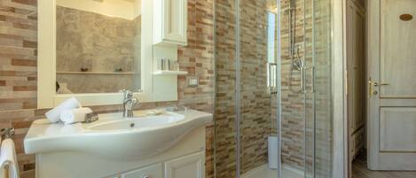 A modern bathroom with a glass-enclosed shower, a large mirror, and a white sink.