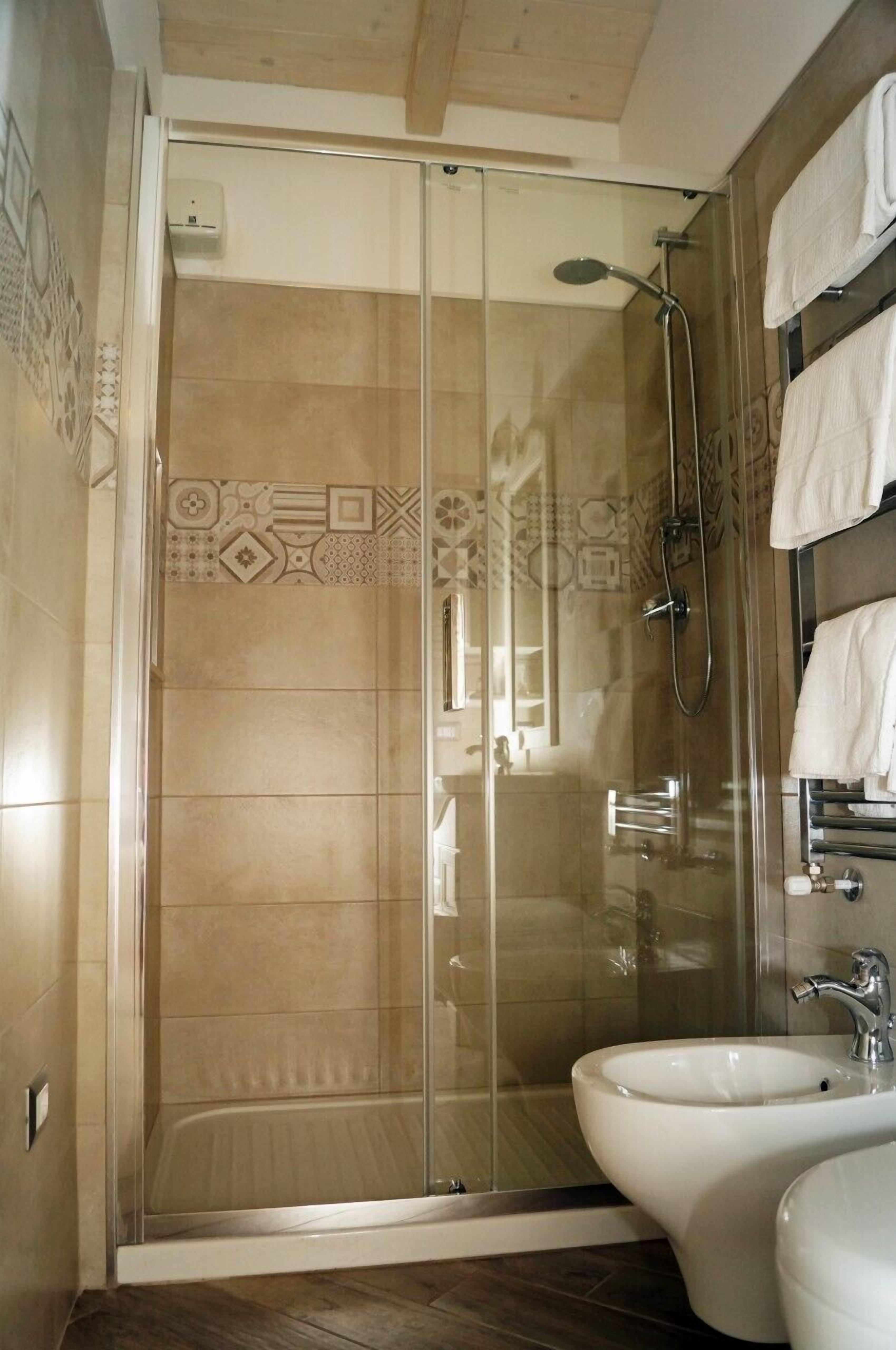 A modern bathroom with a glass-enclosed shower, a white sink, and a towel rack.